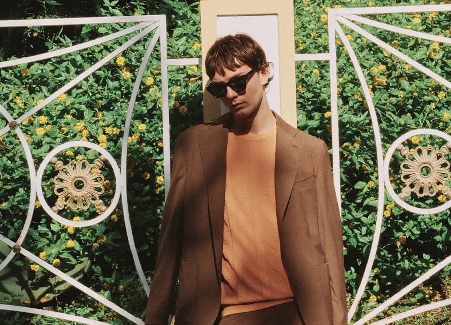 Paul Miranda Sorrento campaign — brown suit against a garden gate